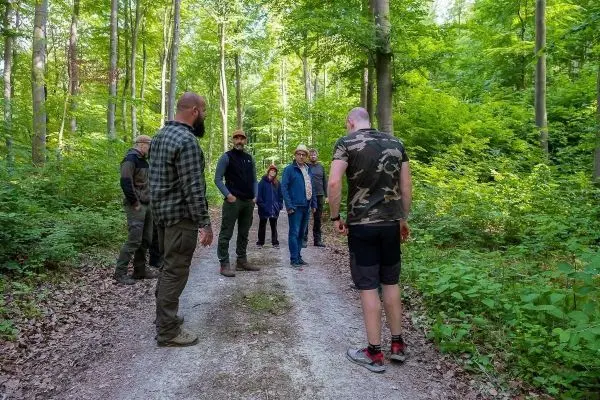 Gruppe steht auf einem Waldweg und diskutiert in einer grünen Umgebung